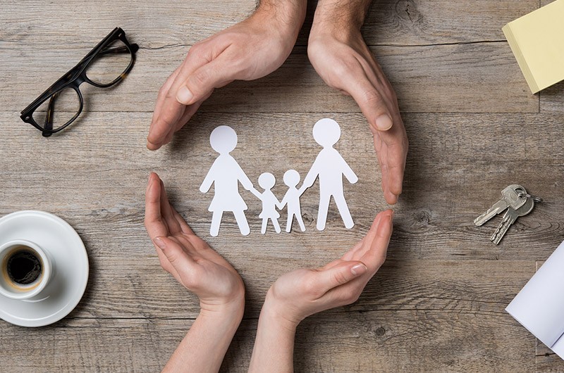 image of cut out of family being protected and surrounded by hands